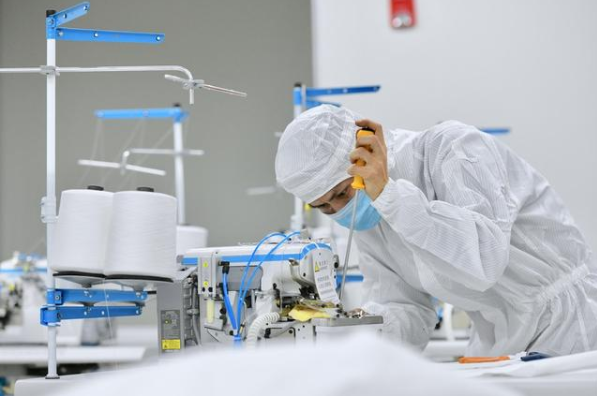 在位于晉江的福建海峽石墨烯產(chǎn)業(yè)技術(shù)研究院的無(wú)菌實(shí)驗(yàn)室，技術(shù)人員在調(diào)試剛剛送達(dá)的防護(hù)服生產(chǎn)設(shè)備。新華社記者姜克紅攝